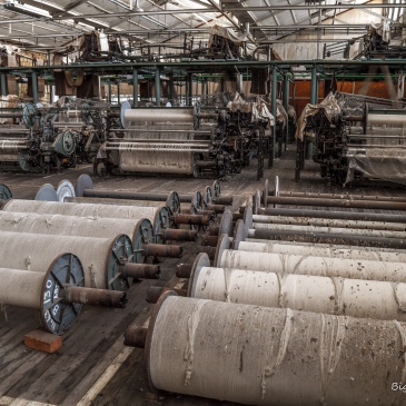 Photo of dilapidated cotton mill with huge rolls of cotton yarn and other machinery