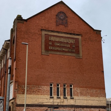 Side of a redbrick building, with a stone panel near the top, with text EW Bryan, Hosiery Manufacturer